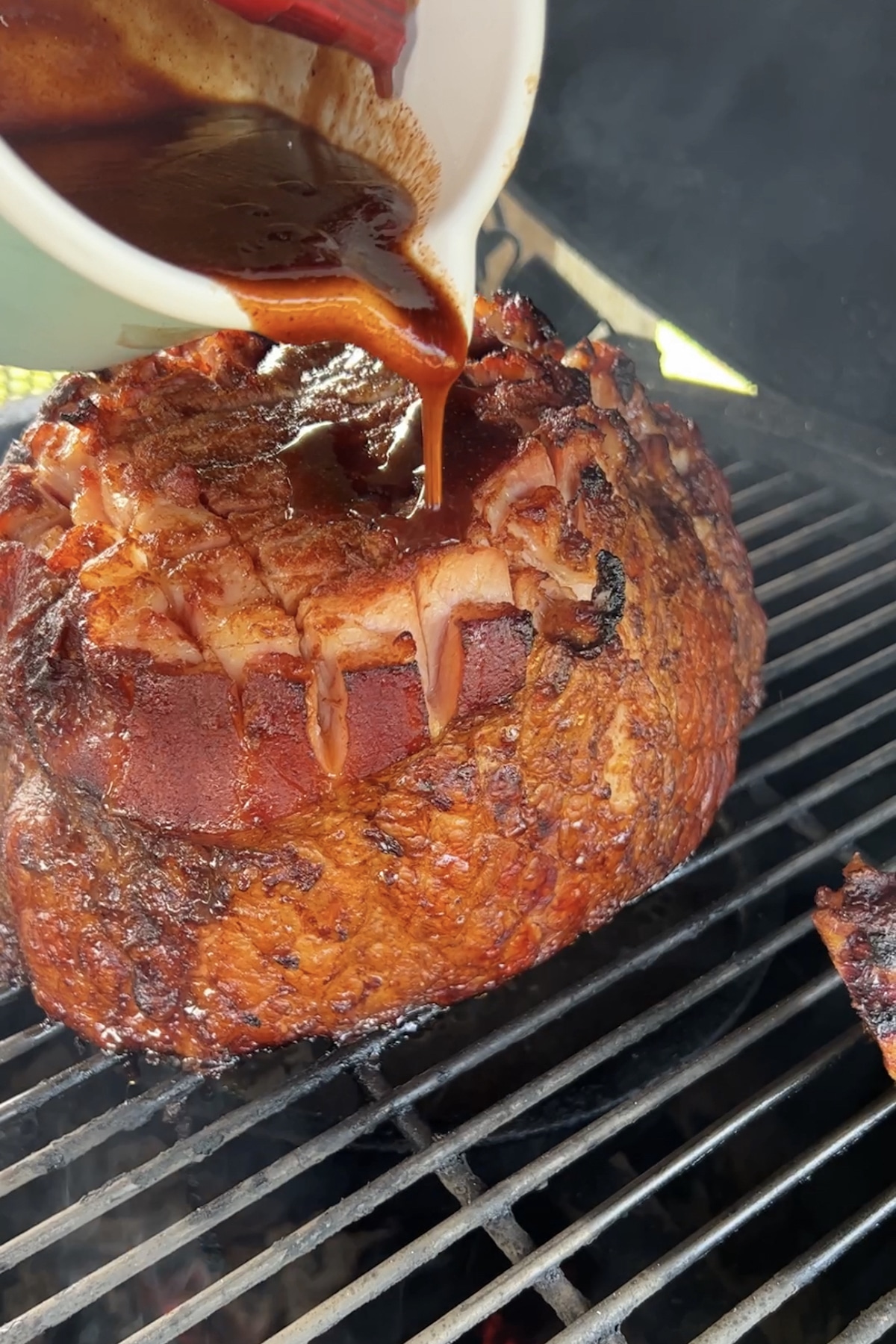 Glazing ham on a grill with blackberry sauce.