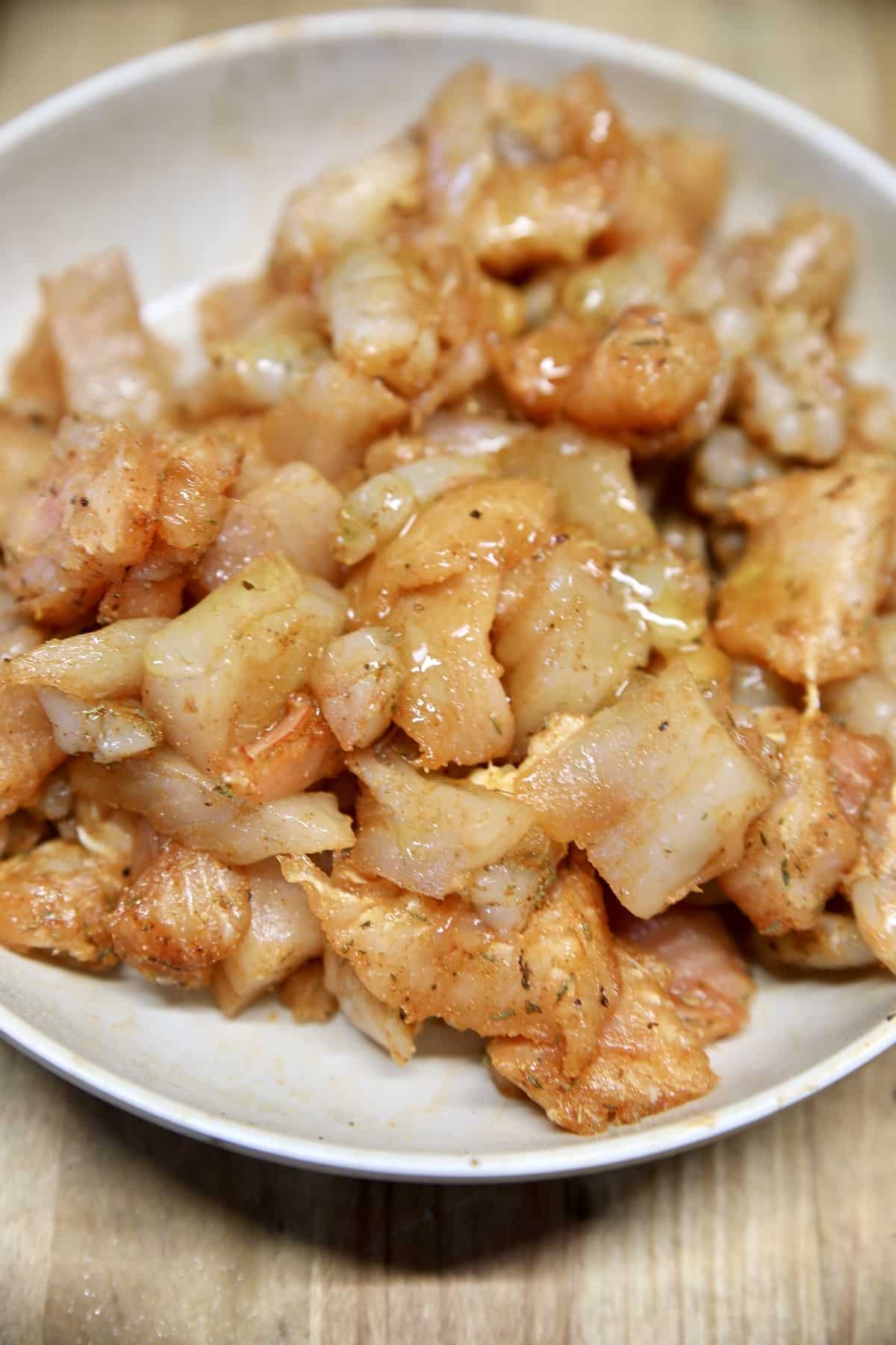 Seasoned shrimp and catfish pieces in a bowl for grilling.