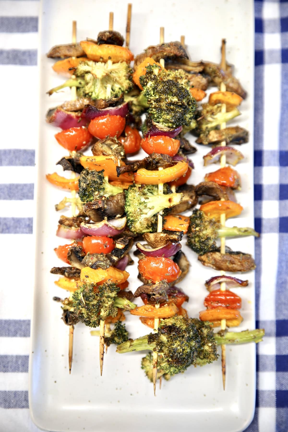 Grilled vegetable skewers on a white platter.