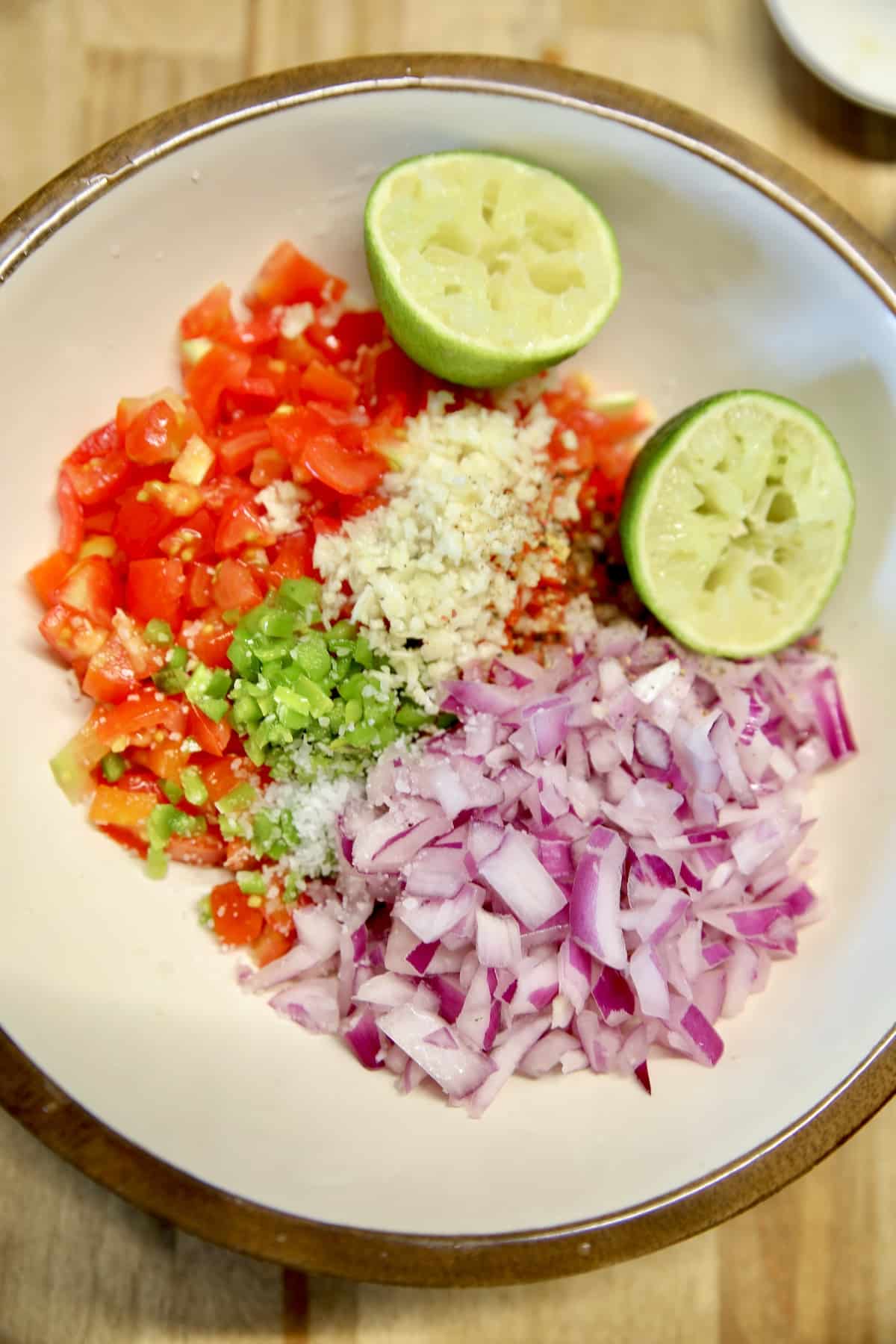 Salsa fresca ingredients in a bowl with squeeze lime.