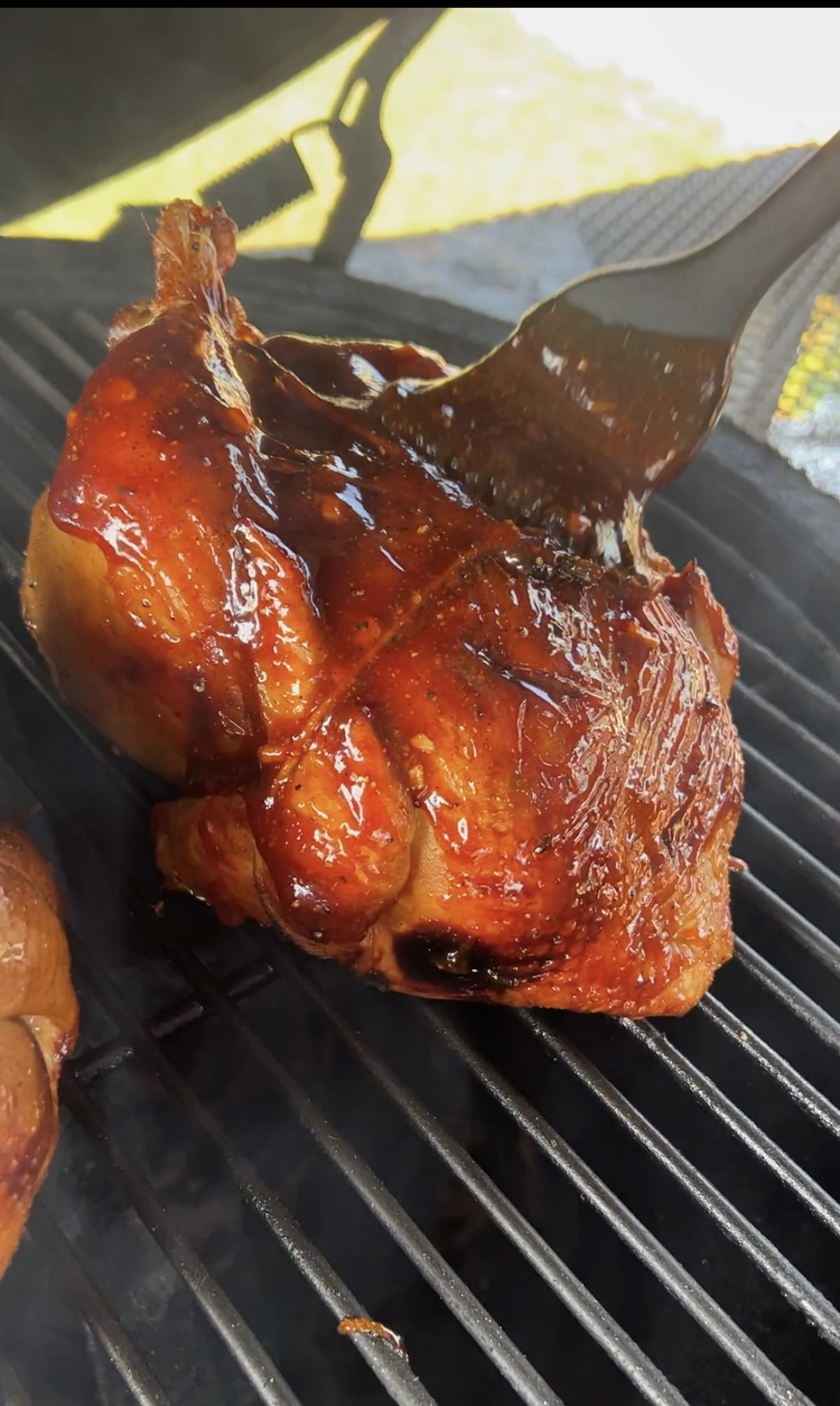 Brushing bbq sauce on whole chicken.