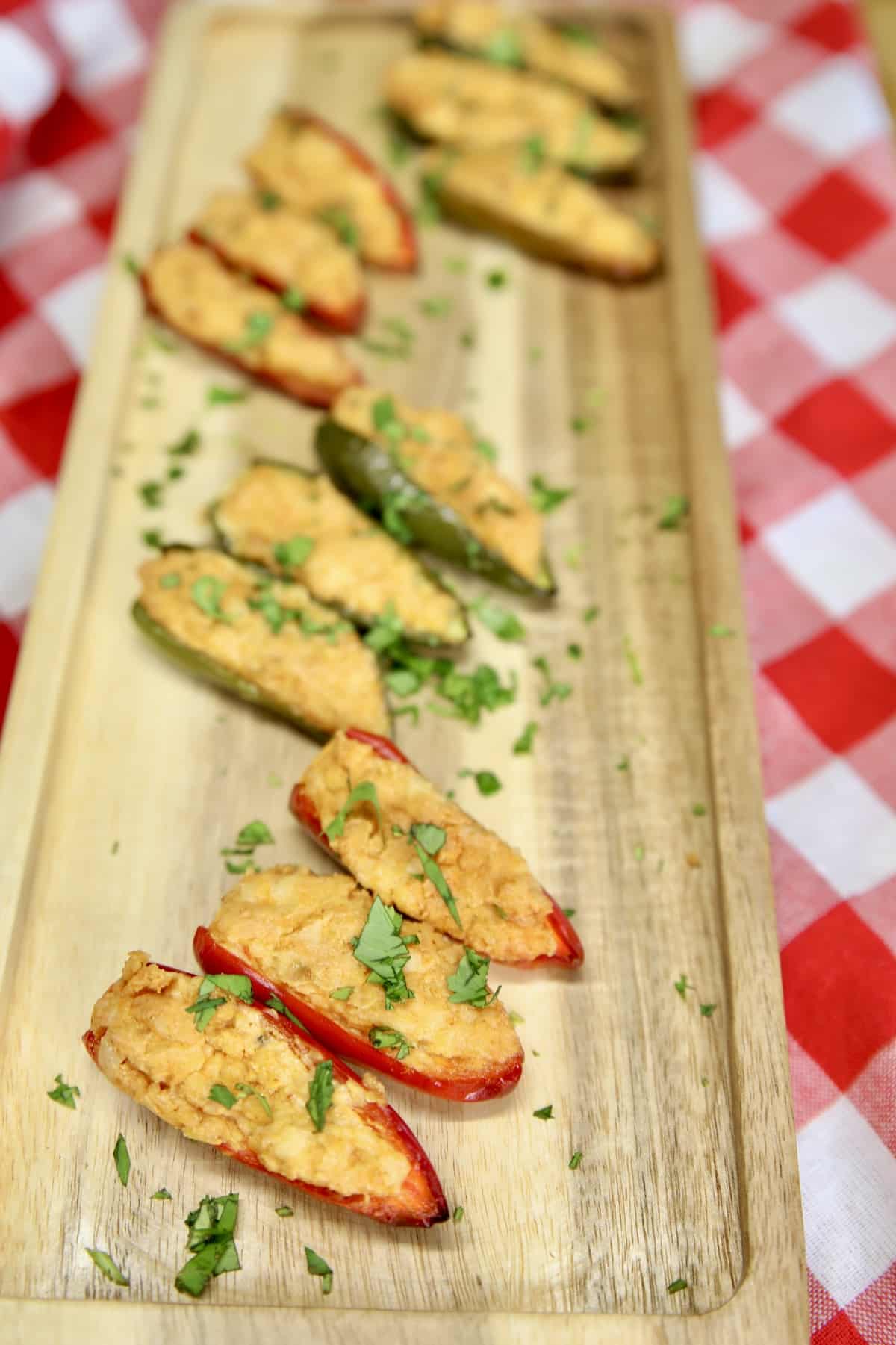 Jalapeno poppers with cheese filling on a serving board.