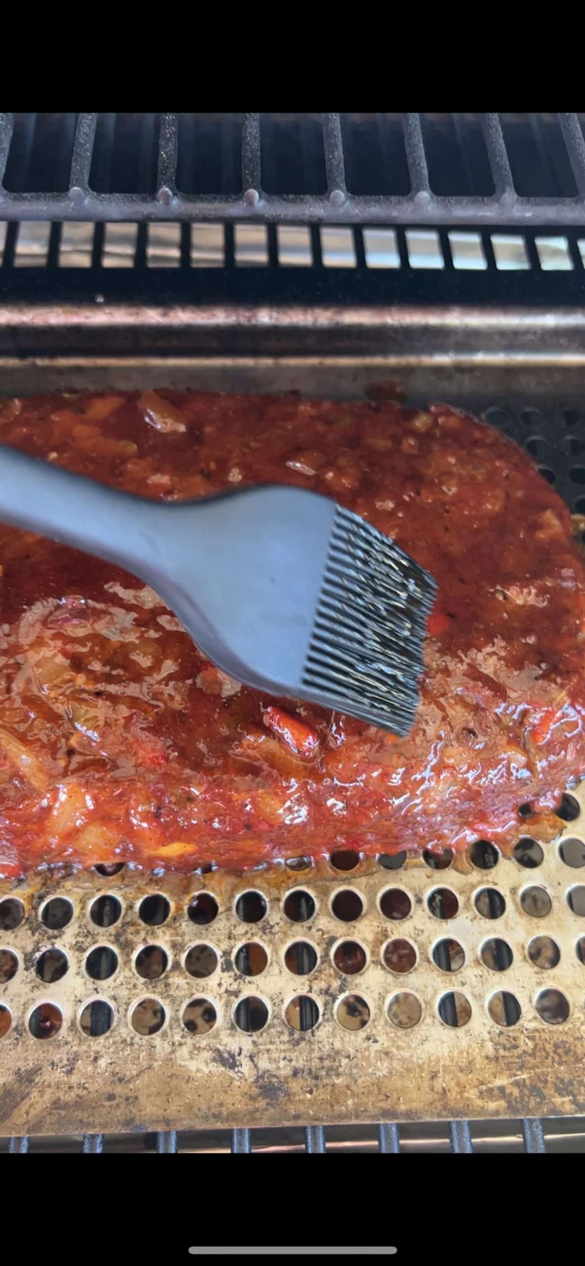 Grilled Meatloaf brushing with bbq sauce.