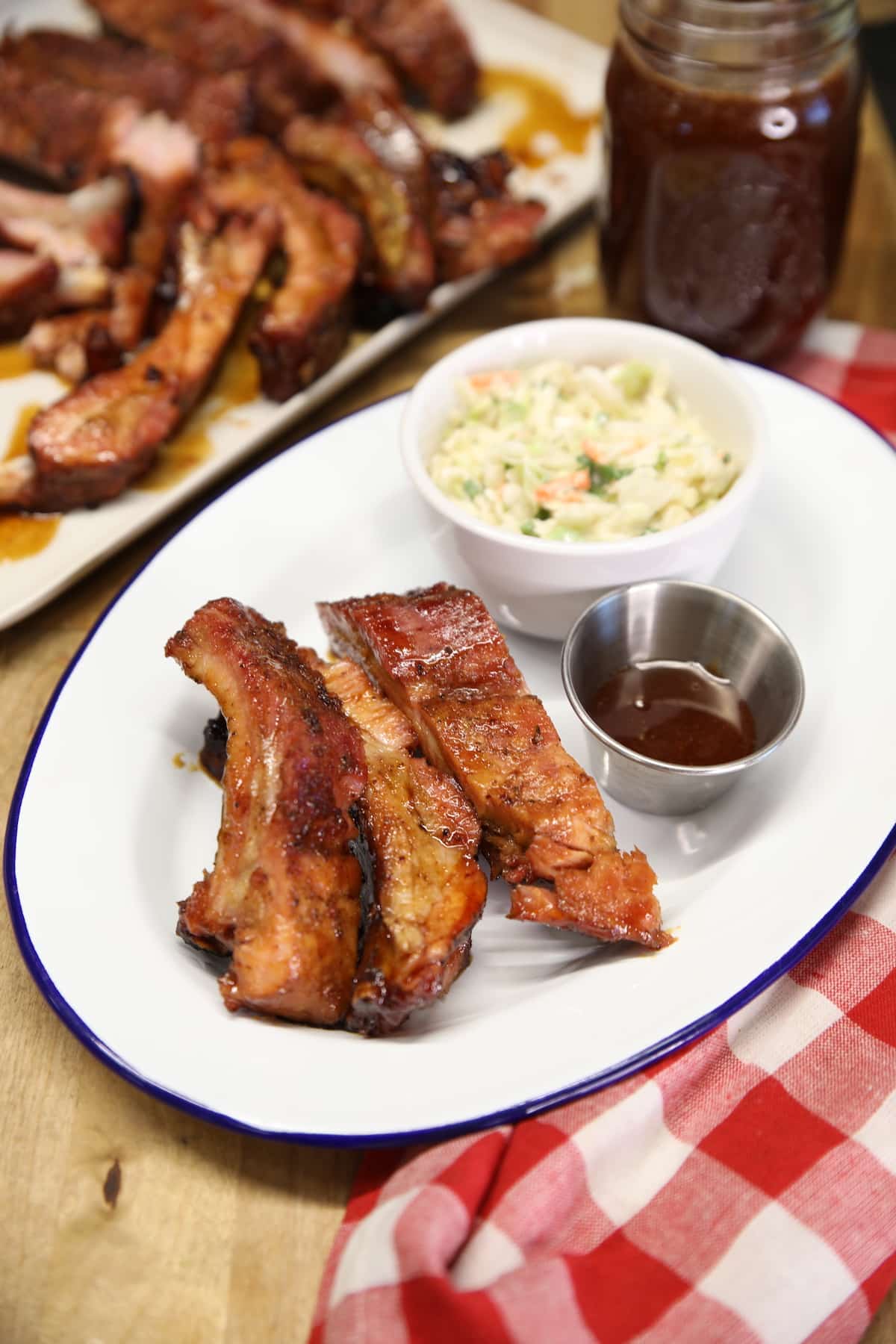 Plate of ribs with sauce with bowl of slaw.
