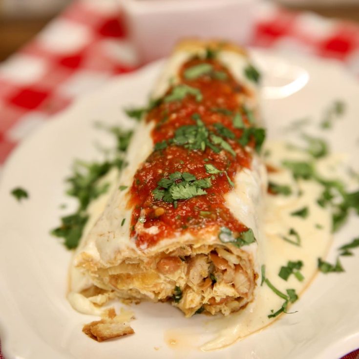 Chicken burrito with sour cream sauce and salsa, end removed to see filling.