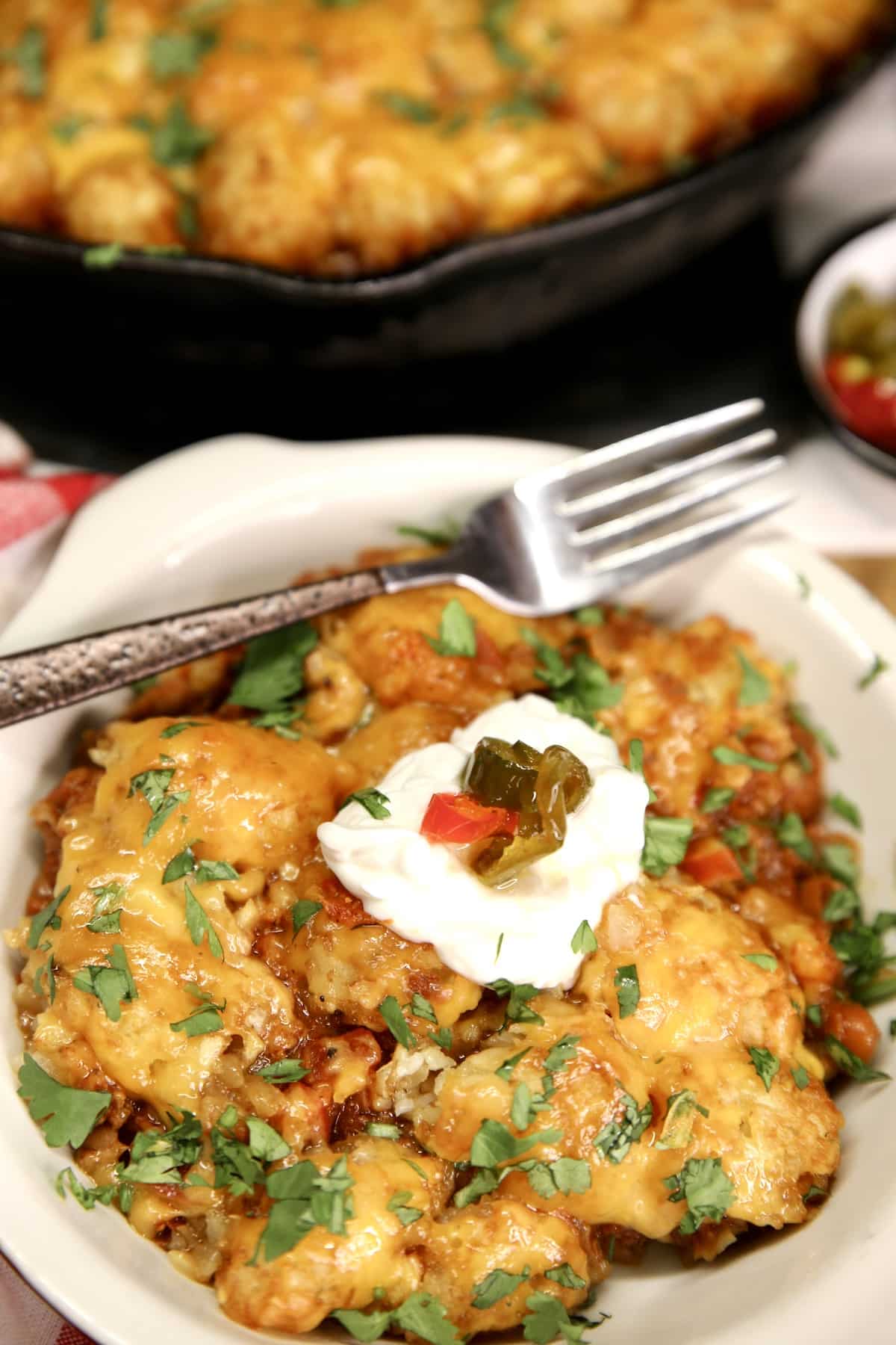 Chili Cheese Tater Tot Casserole in a dish with sour cream and jalapenos.