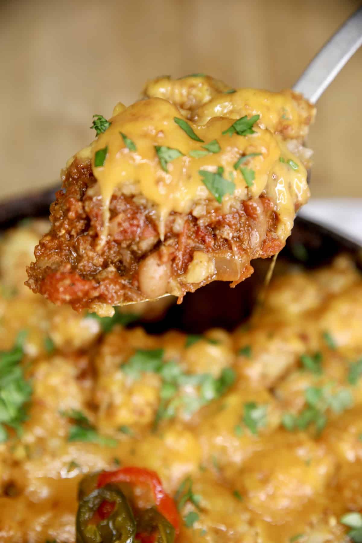 Serving chili cheese tater tot casserole on a spoon.