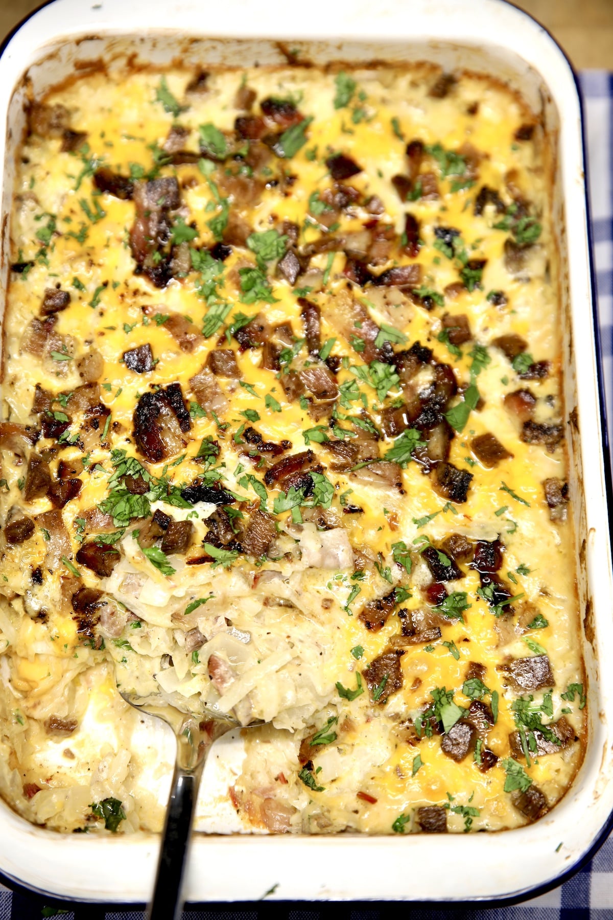 Hashbrown casserole with brisket in a baking dish, spatula serving.