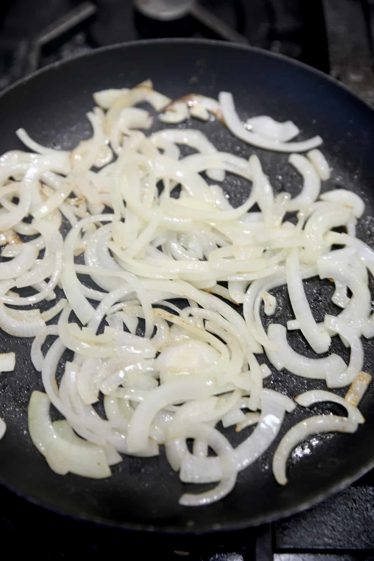 Cooking sliced onions in a skillet.