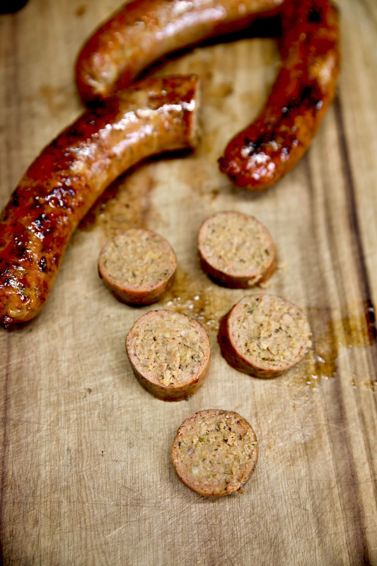 Smoked Italian Sausage links, one sliced on a cutting board.