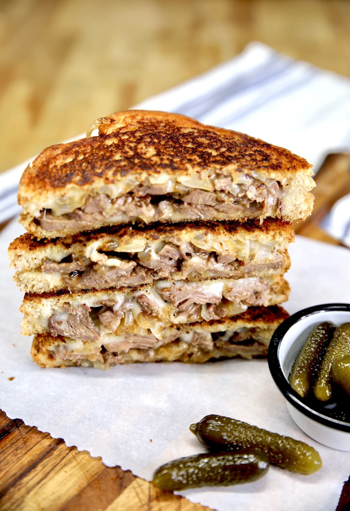 Steak and onion Swiss grilled cheese sandwiches, stacked.