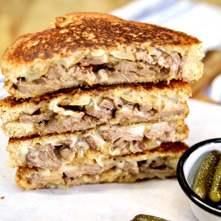 Stacked steak grilled cheese sandwiches cut in half.