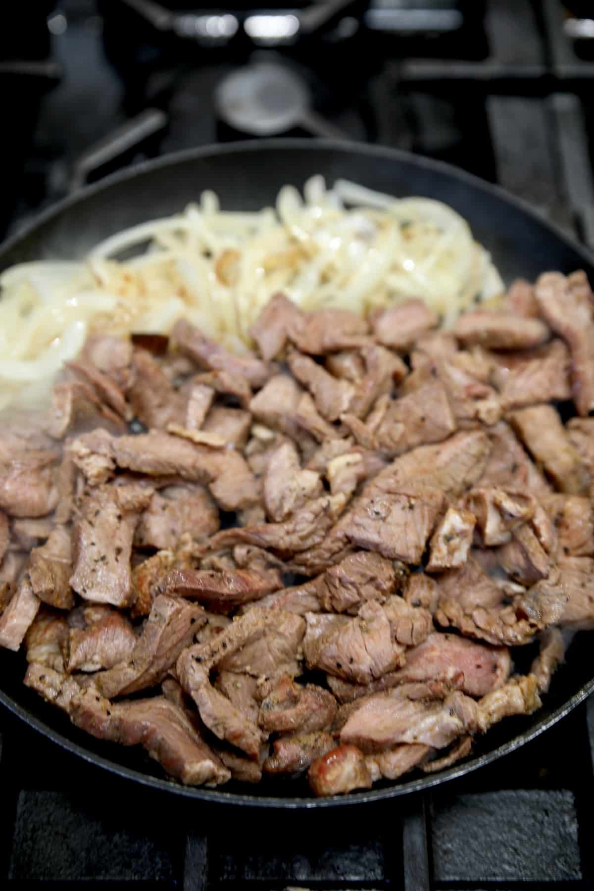 Skillet with onions and sliced steak.