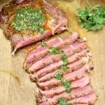 Grilled steak, partially sliced, topped with chimichurri sauce.