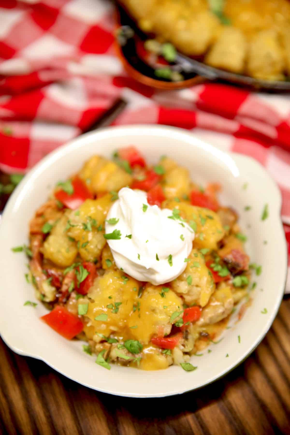 Bowl of cowboy casserole with course cream and tomatoes.