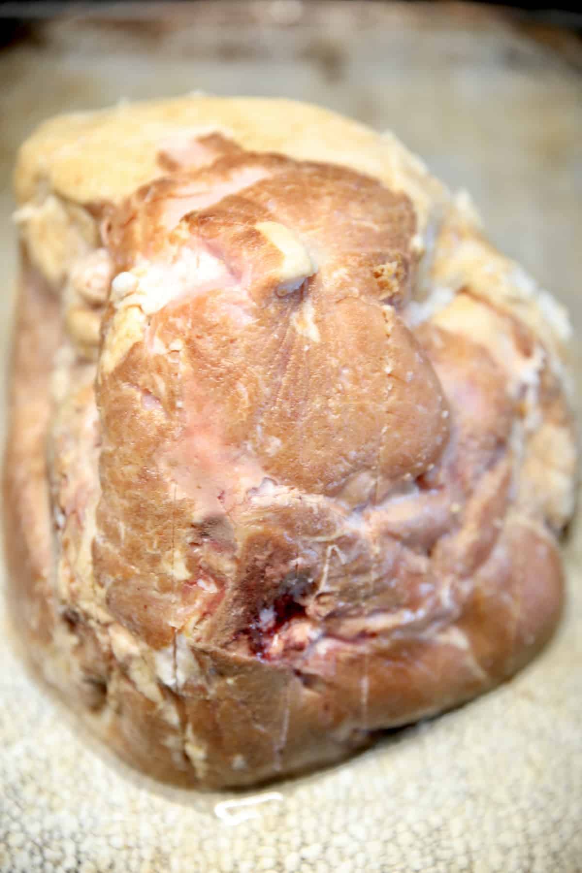 Half ham on a baking sheet, scored in a crosshatch pattern.