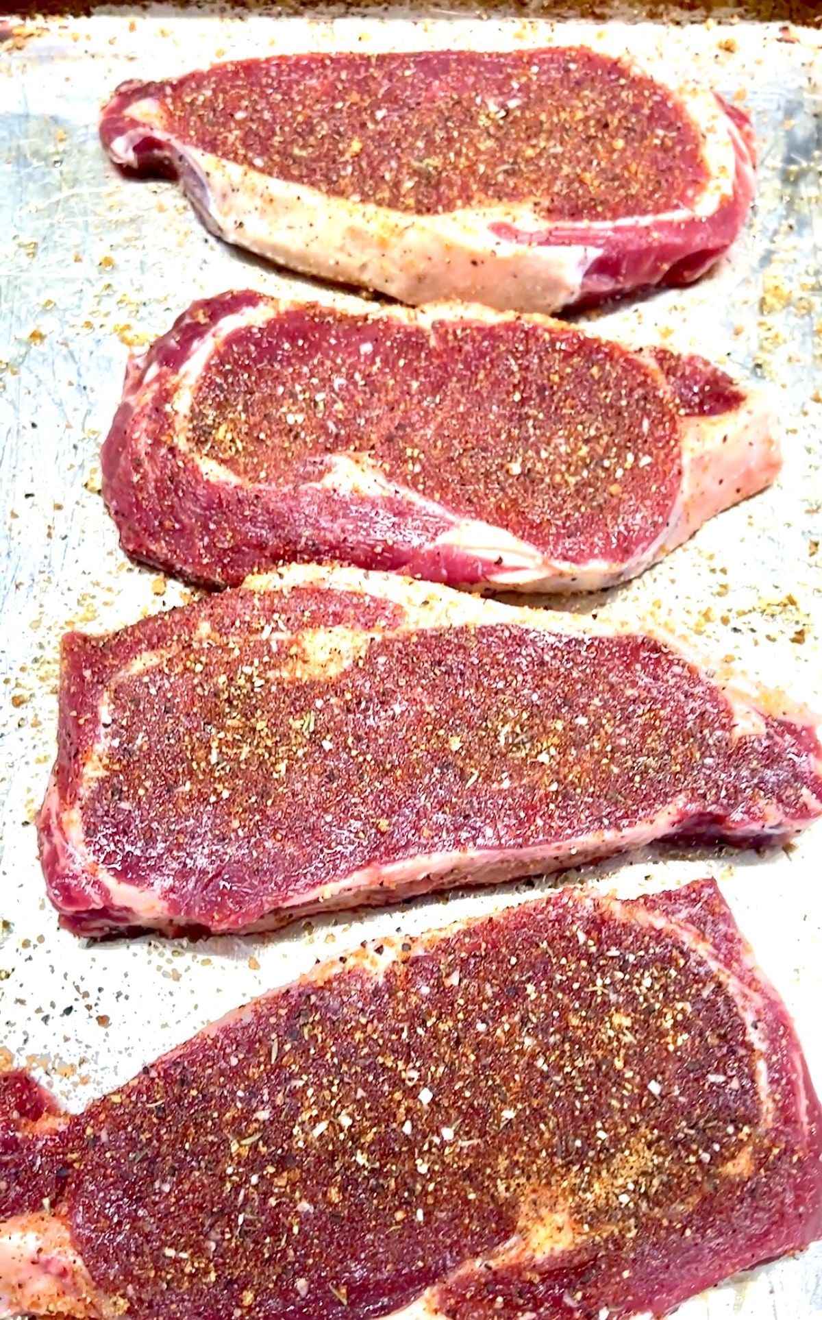Seasoned ribeye steaks ready to grill.