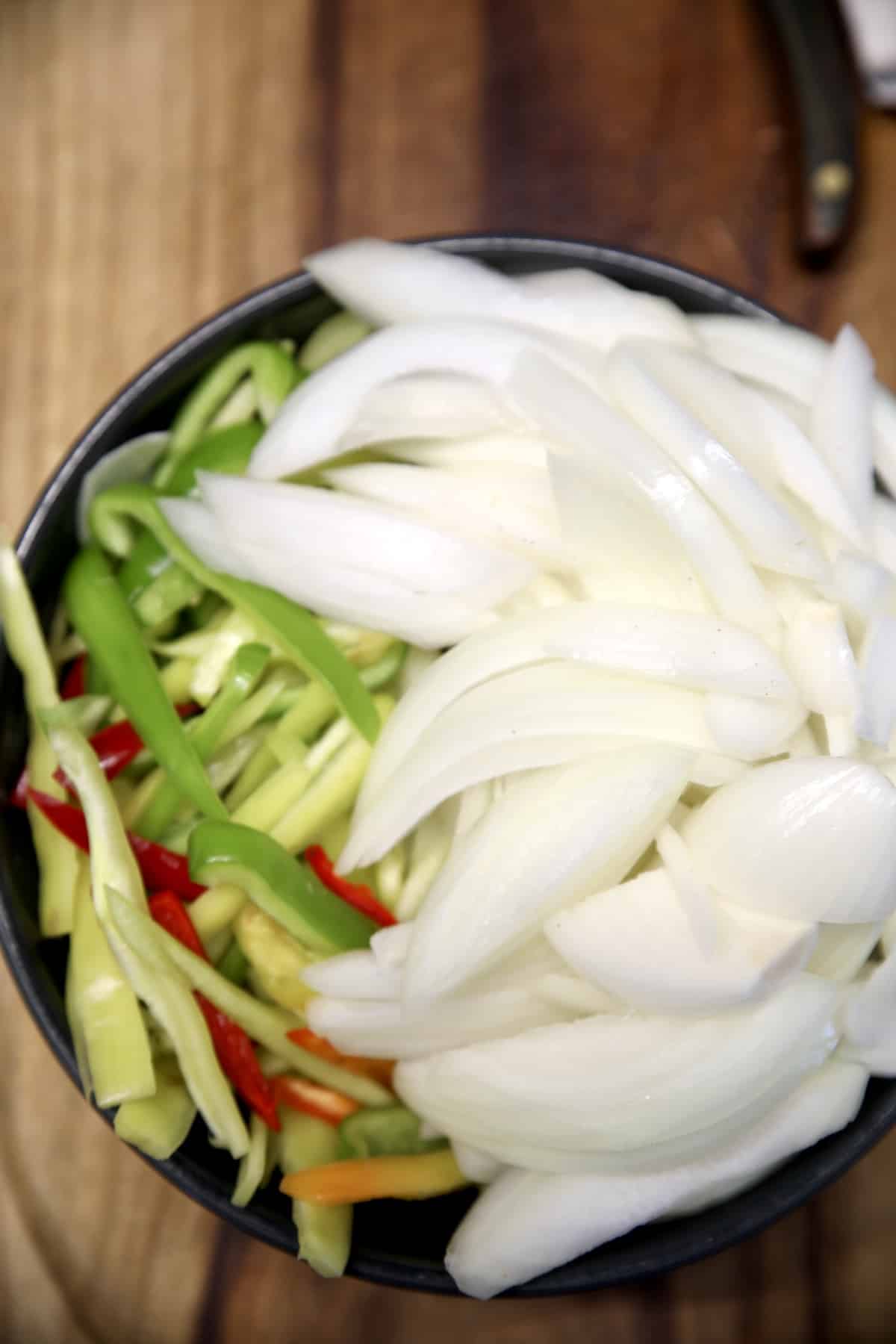 Sliced peppers, onions in a bowl.