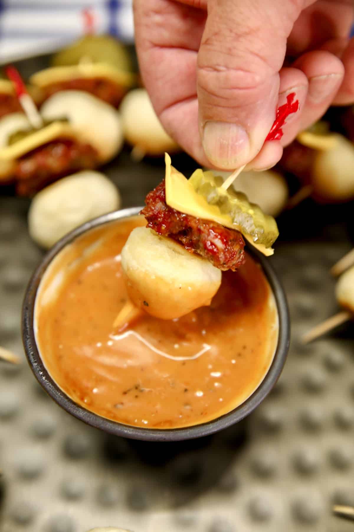 Burger appetizer dipping into sauce. 