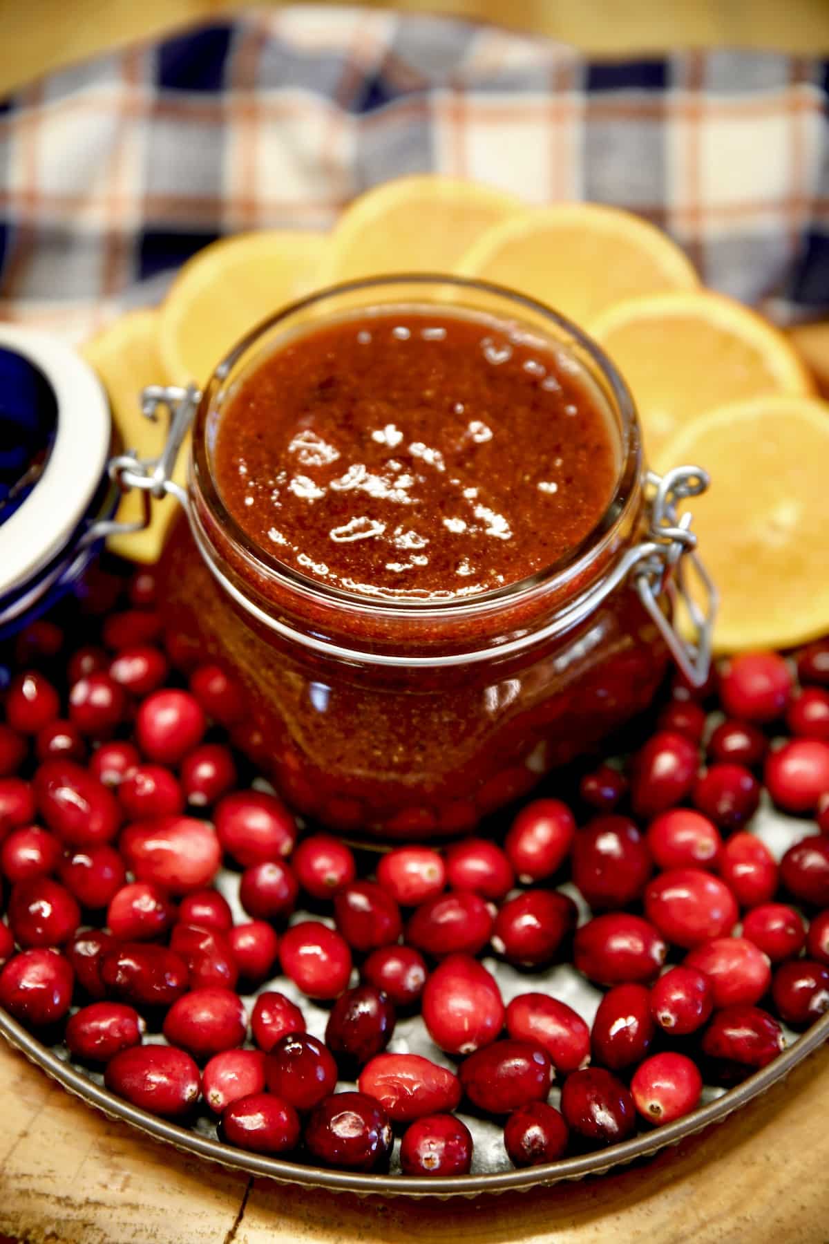 Cranberry orange sauce in a jar, orange slices and fresh cranberries on a platter.