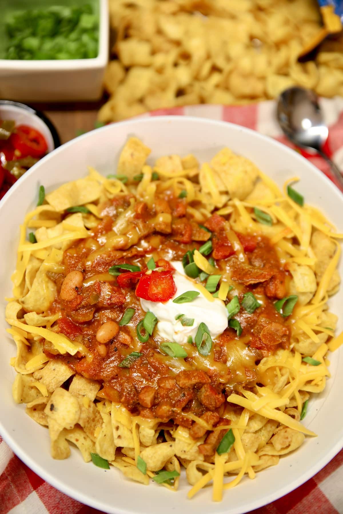 Bowl of frito chili pie with sour cream and candied jalapenos.