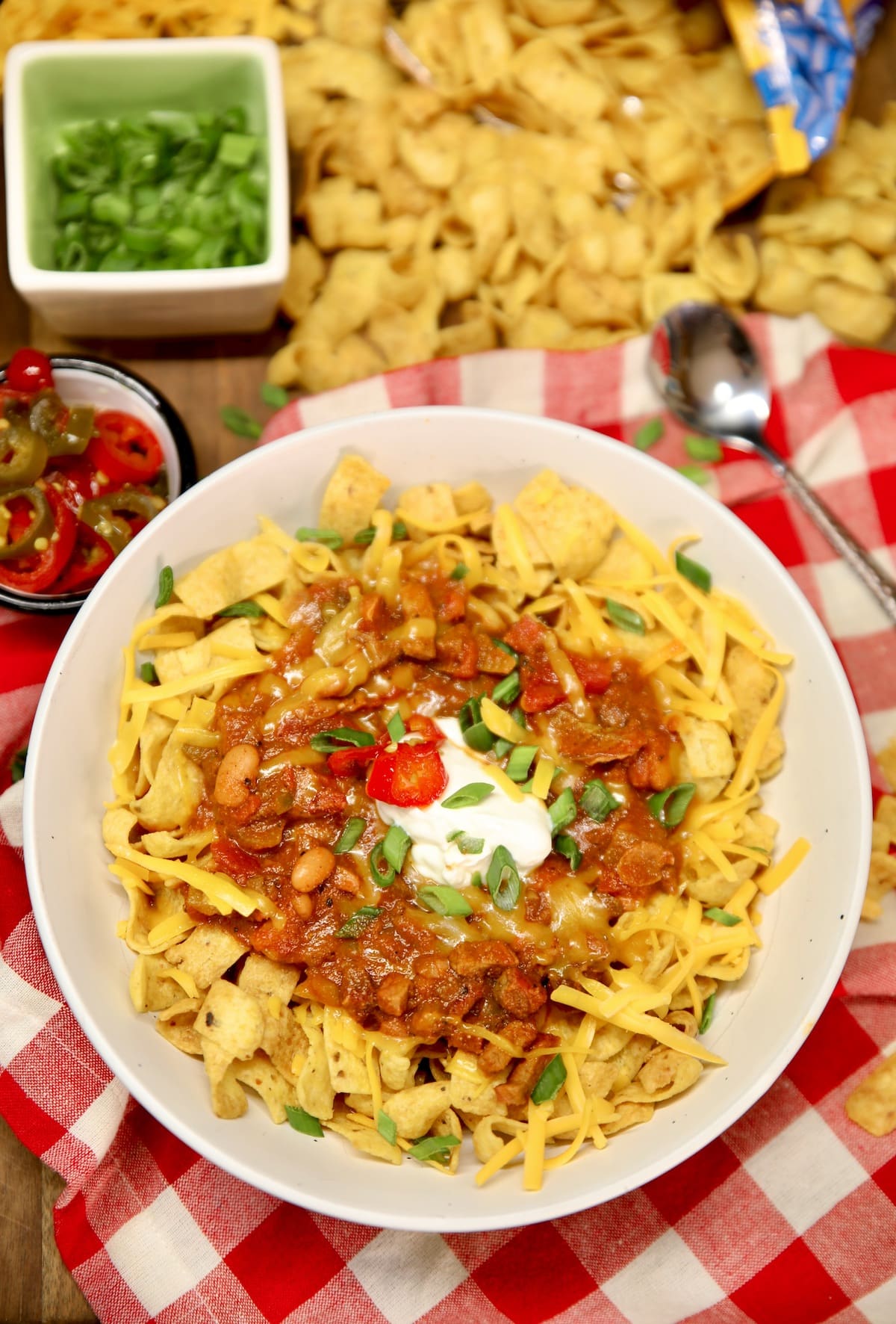 Bowl of frito chili pie with green onions and sour cream.