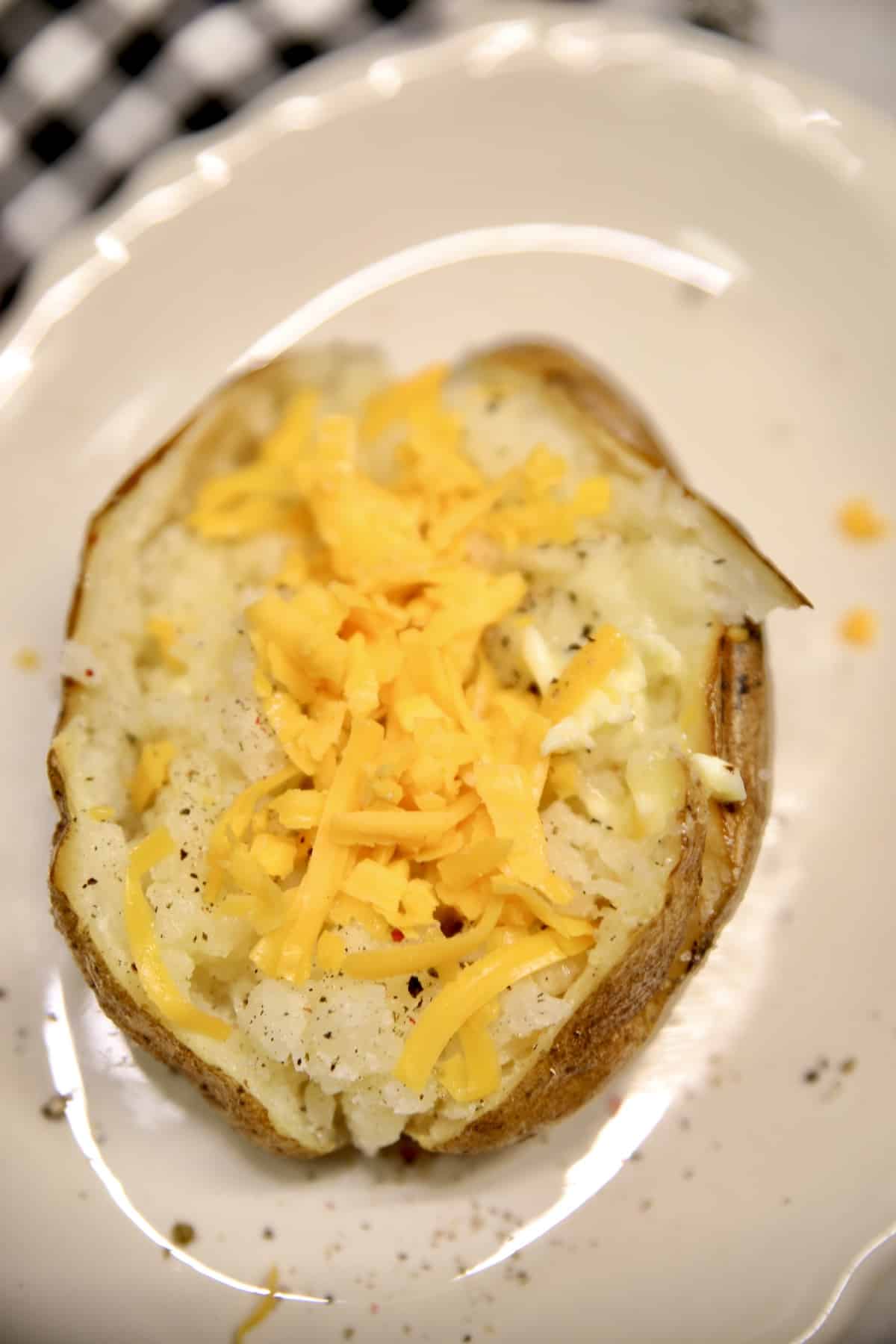 Baked potato with butter and shredded cheese.