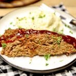 2 slices bbq meatloaf on a plate with mashed potatoes.