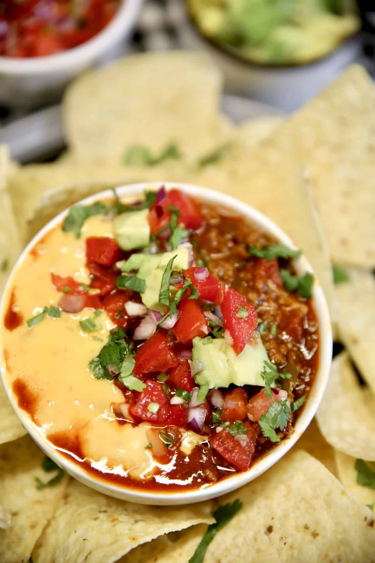 Bowl of chili queso dip with chips.
