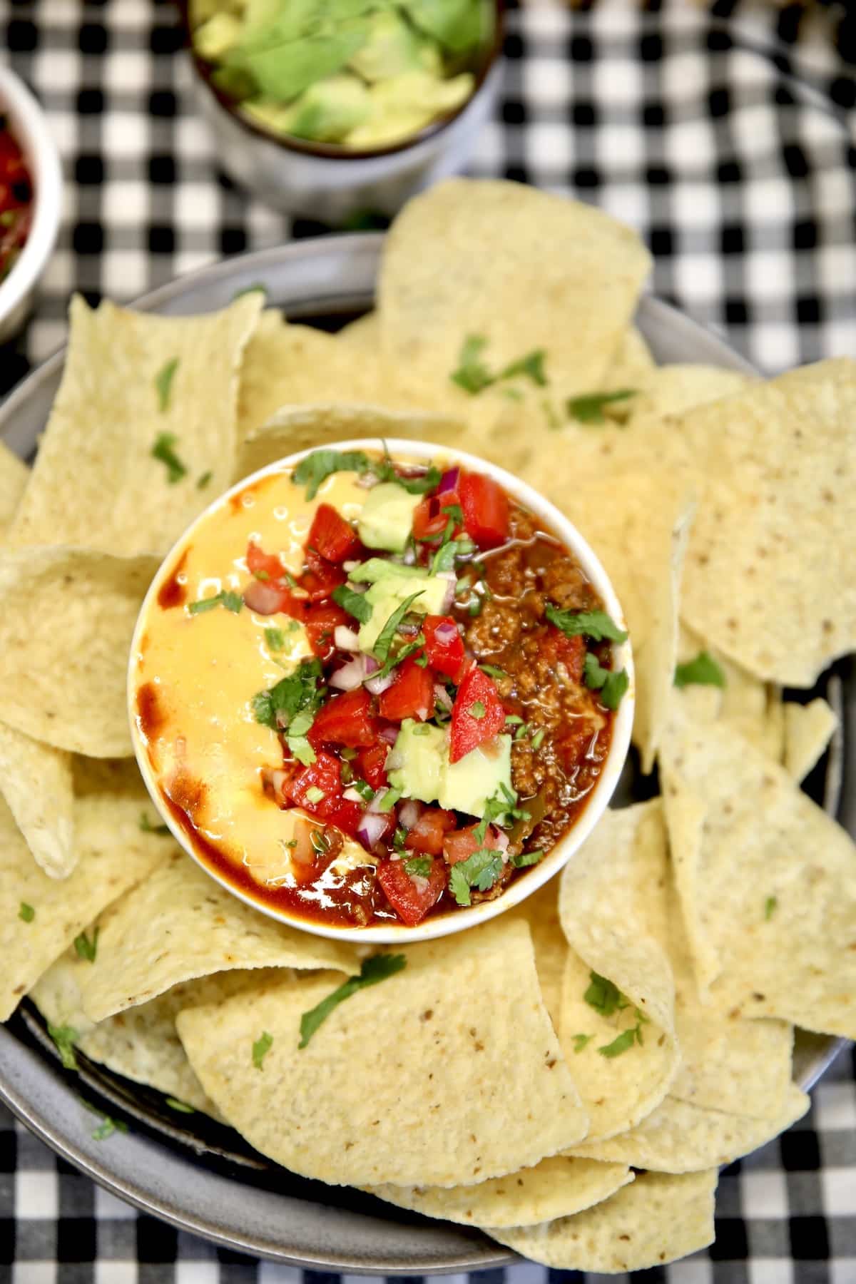 Platter of tortilla chips with chili cheese dip.