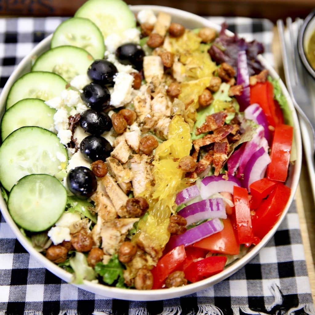 Greek salad with grilled chicken in a bowl.