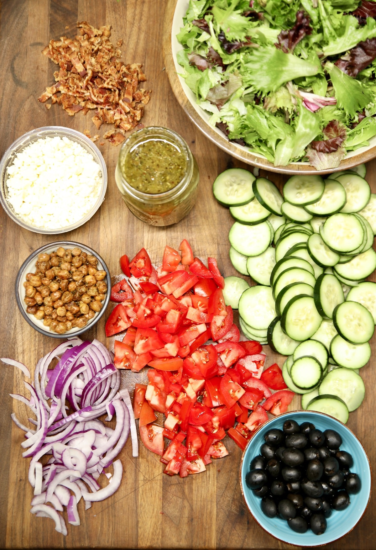 Greek salad board with lettuce, onions, tomatoes, cucumbers.