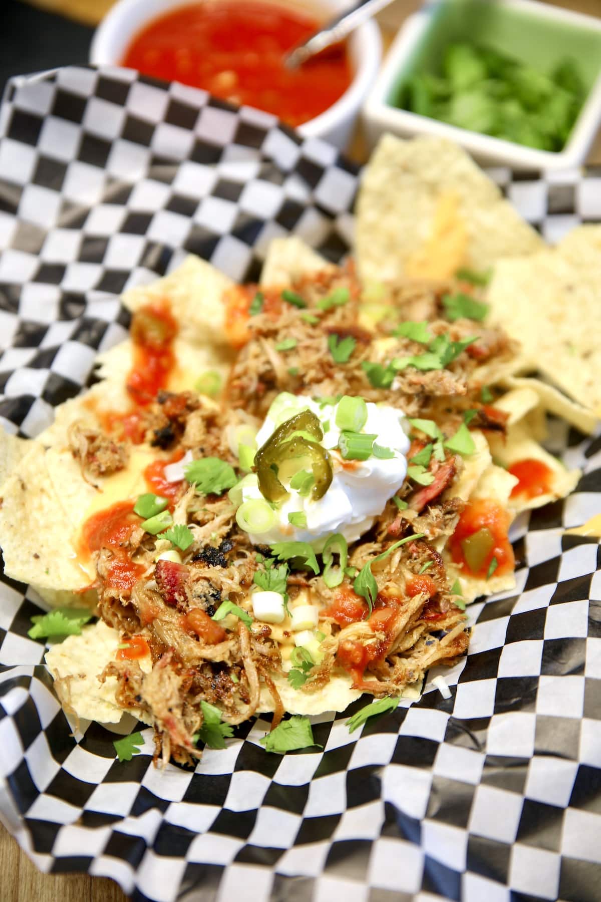 Pulled pork nachos on a checked paper lined basket.
