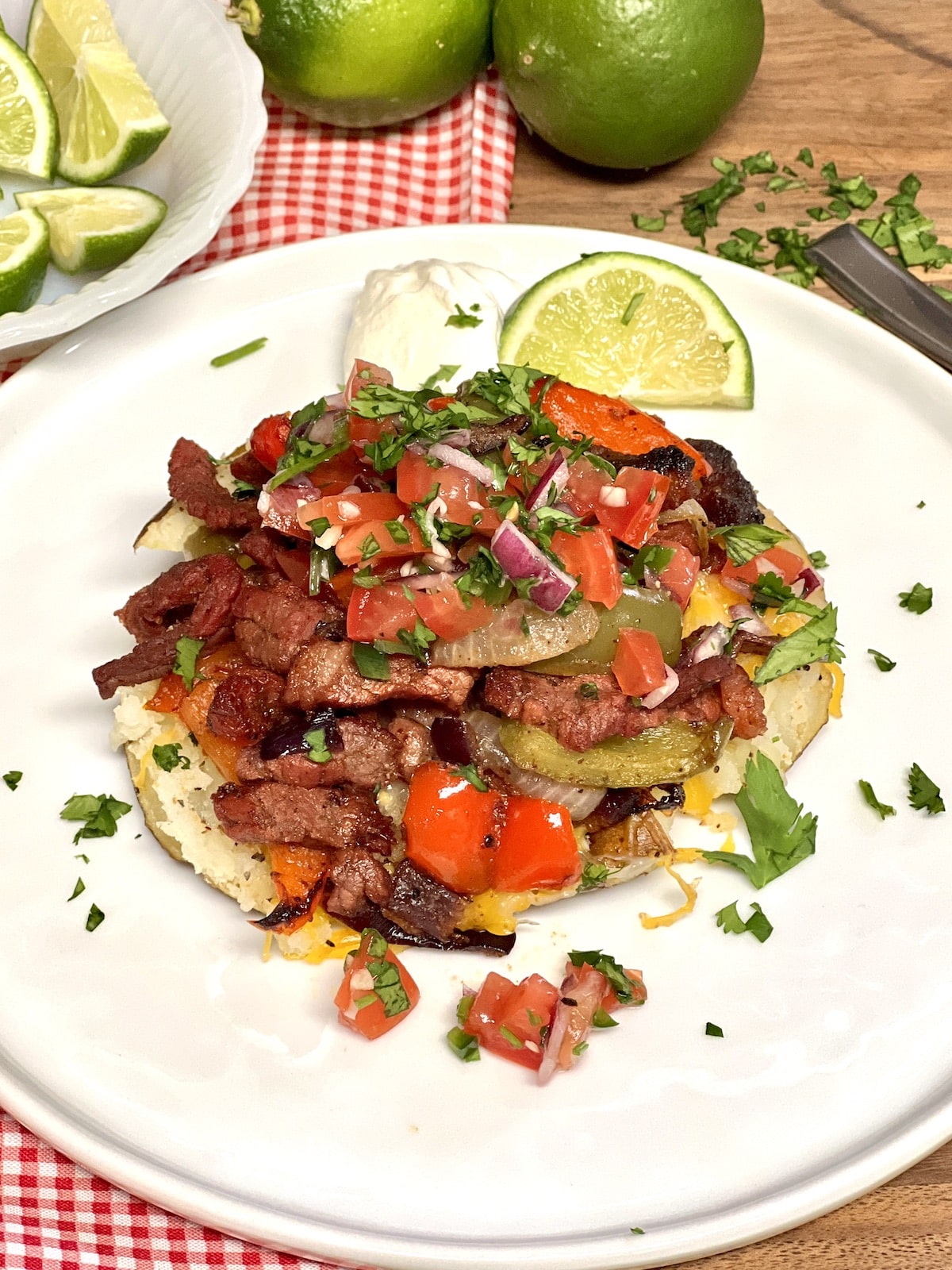 Loaded baked potato on a plate topped with beef fajita mixture.