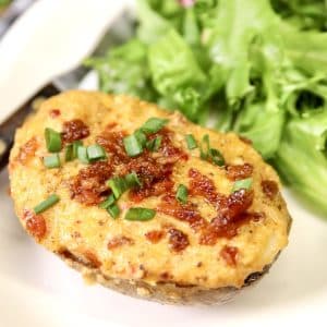 Pimento cheese baked potato on a plate with salad greens.