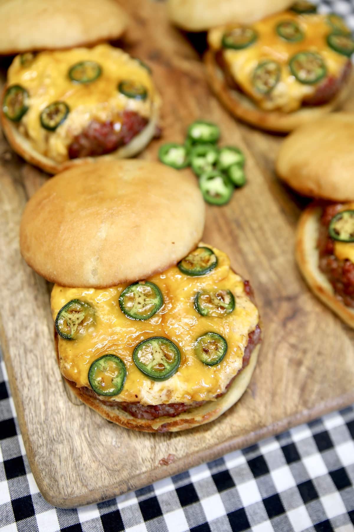 Grilled burgers on a board with jalapeno topping.