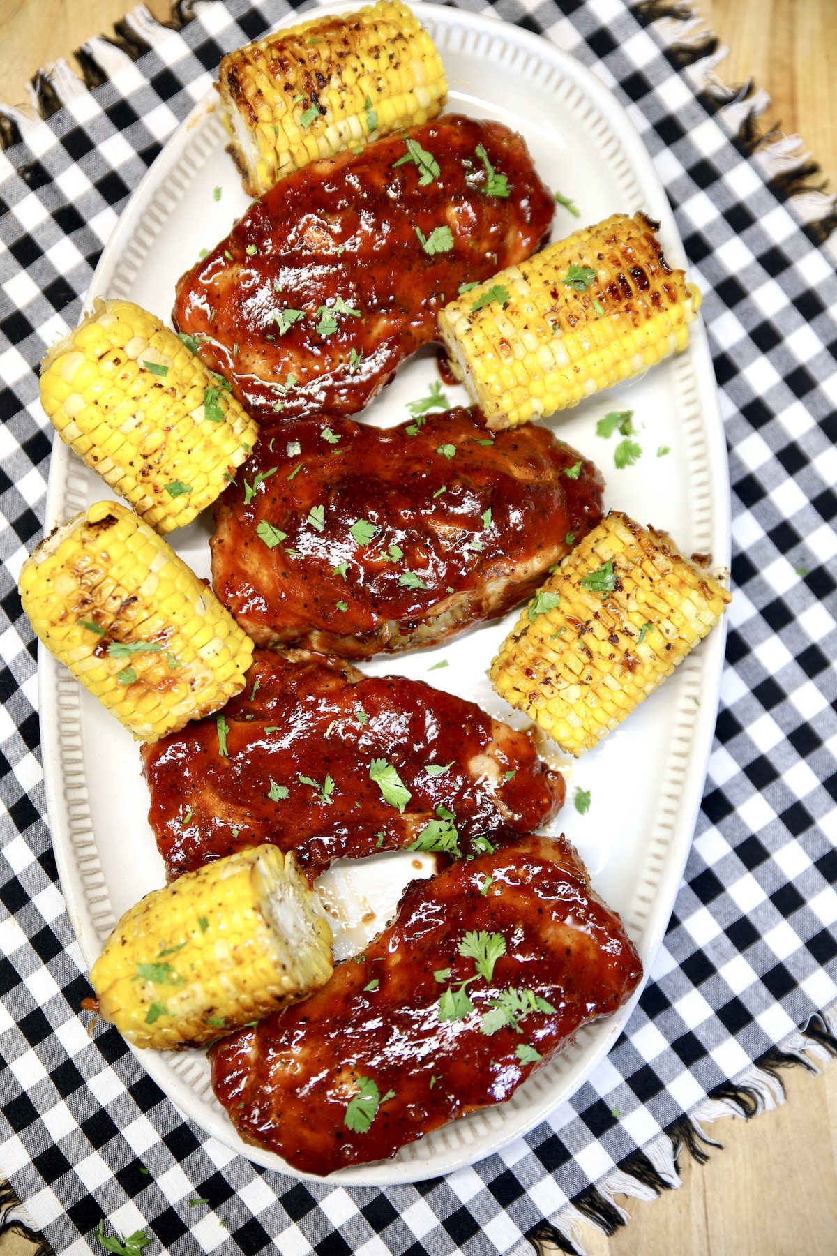 Platter of bbq pork chops and corn on the cob.