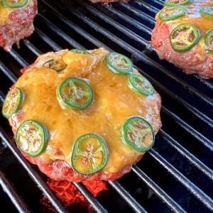 Jalapeno popper stuffed burger on a grill.