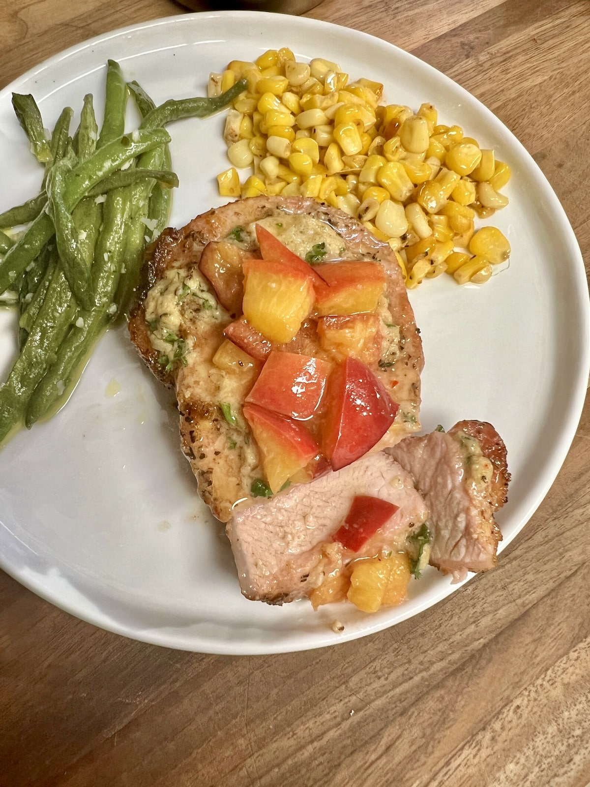 Grilled pork chops with grilled peaches on a plate  with vegetables.