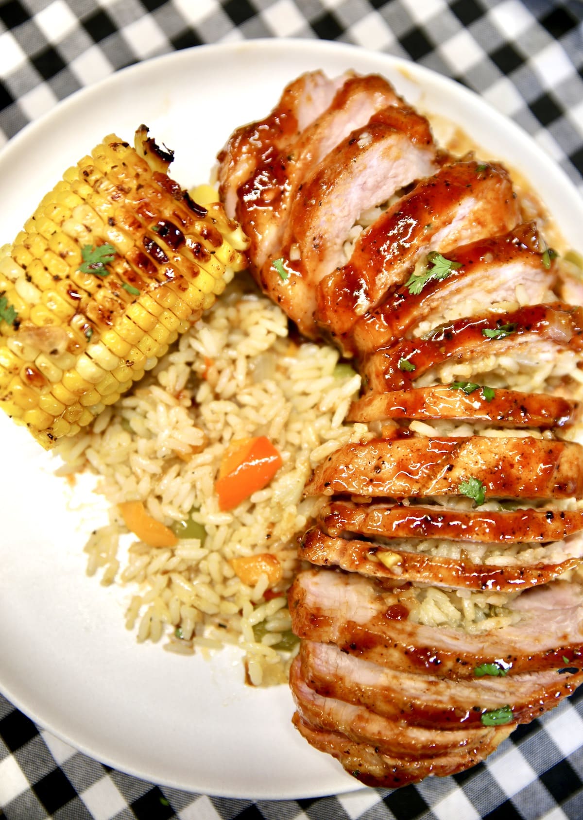 Plate with bbq sliced pork chop with rice and corn.
