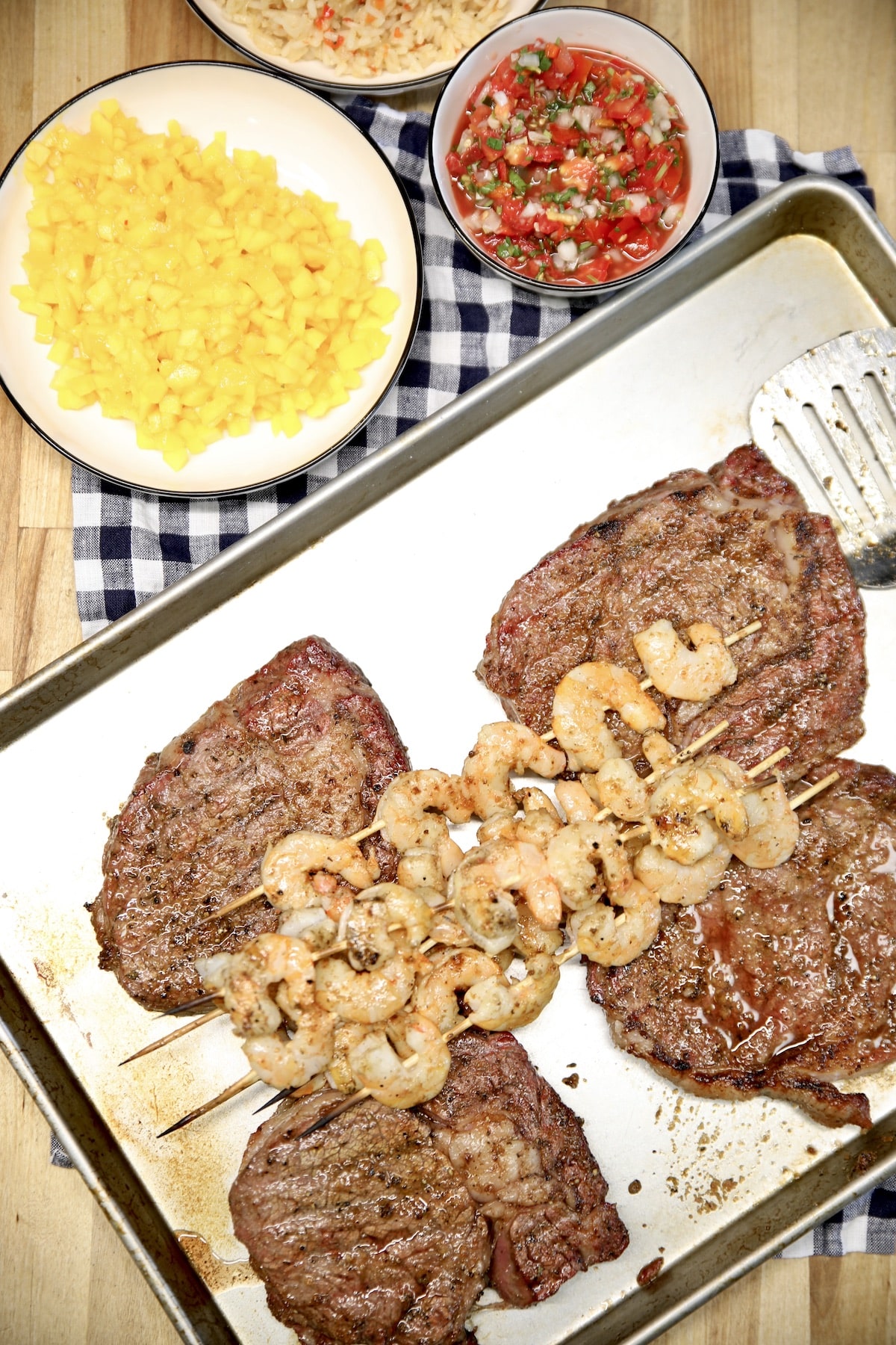 Platter of grilled steaks with shrimp skewers, salsa, mango. 