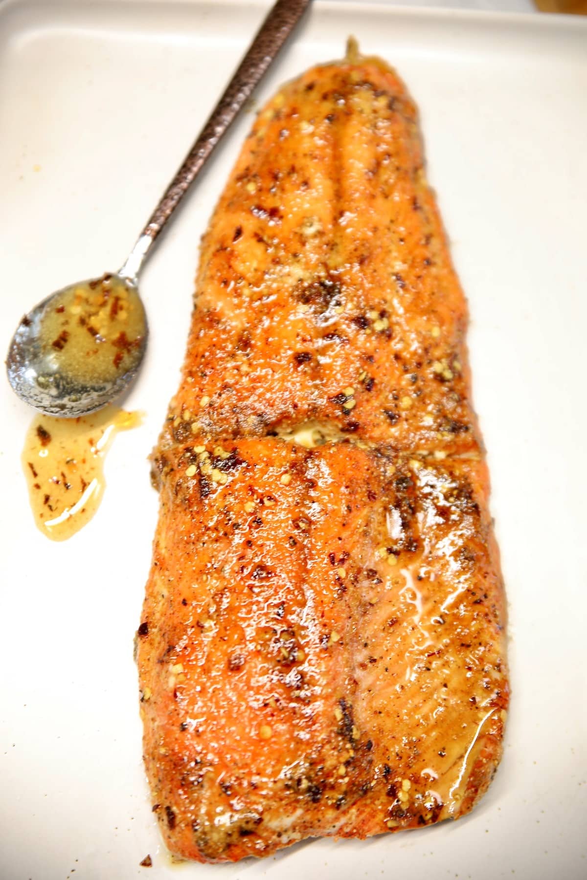 Hot honey glazed salmon on a platter with spoon of honey.