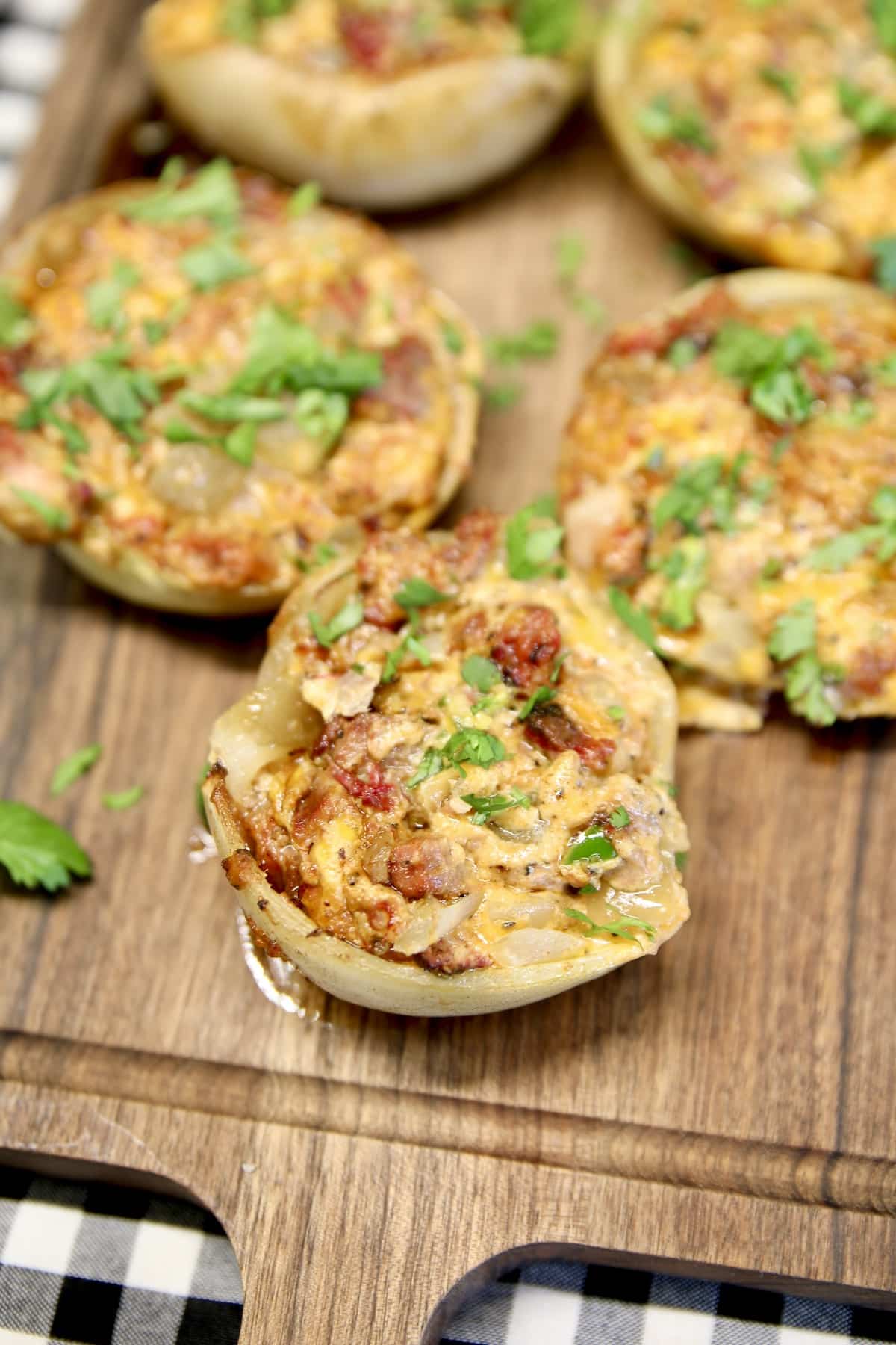 Brisket stuffed onions with cheesy filling on a board.