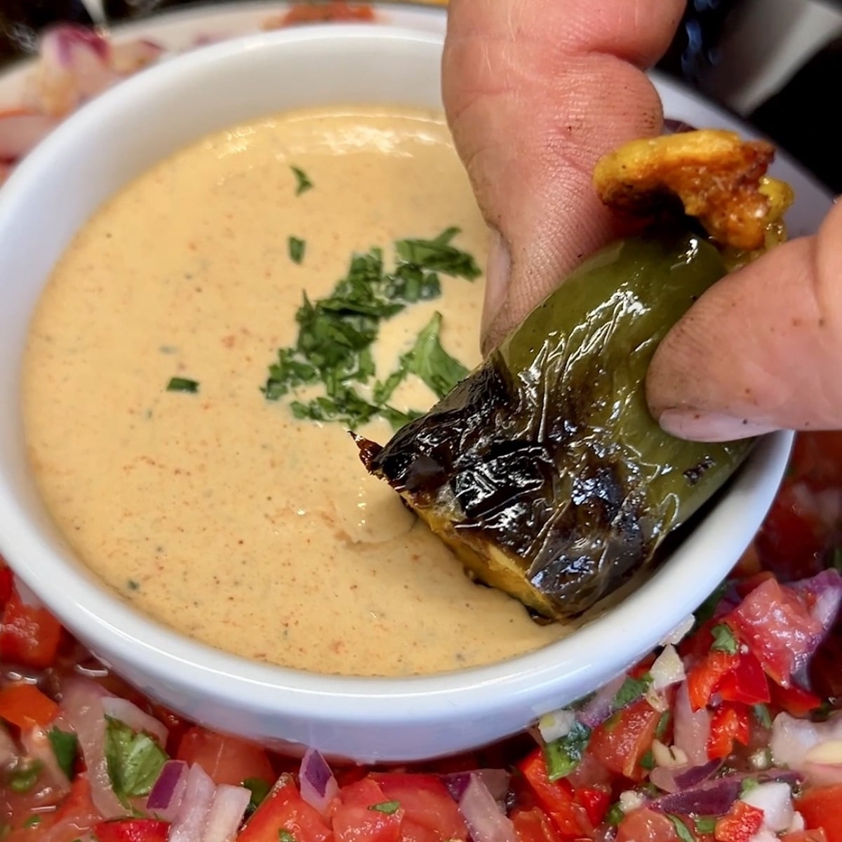 Dipping jalapeno popper into dip.