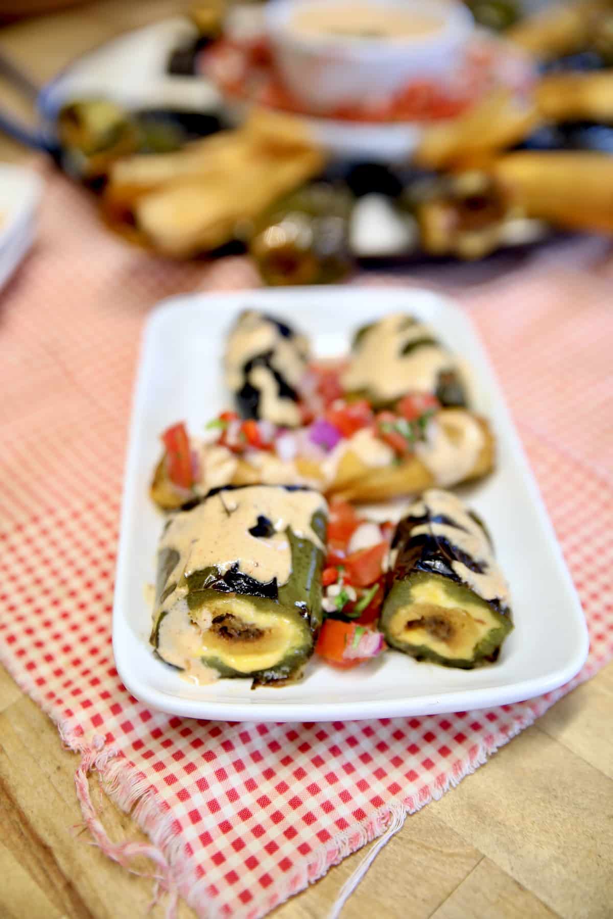 Jalapeno poppers with cheese and tamales on a plate.