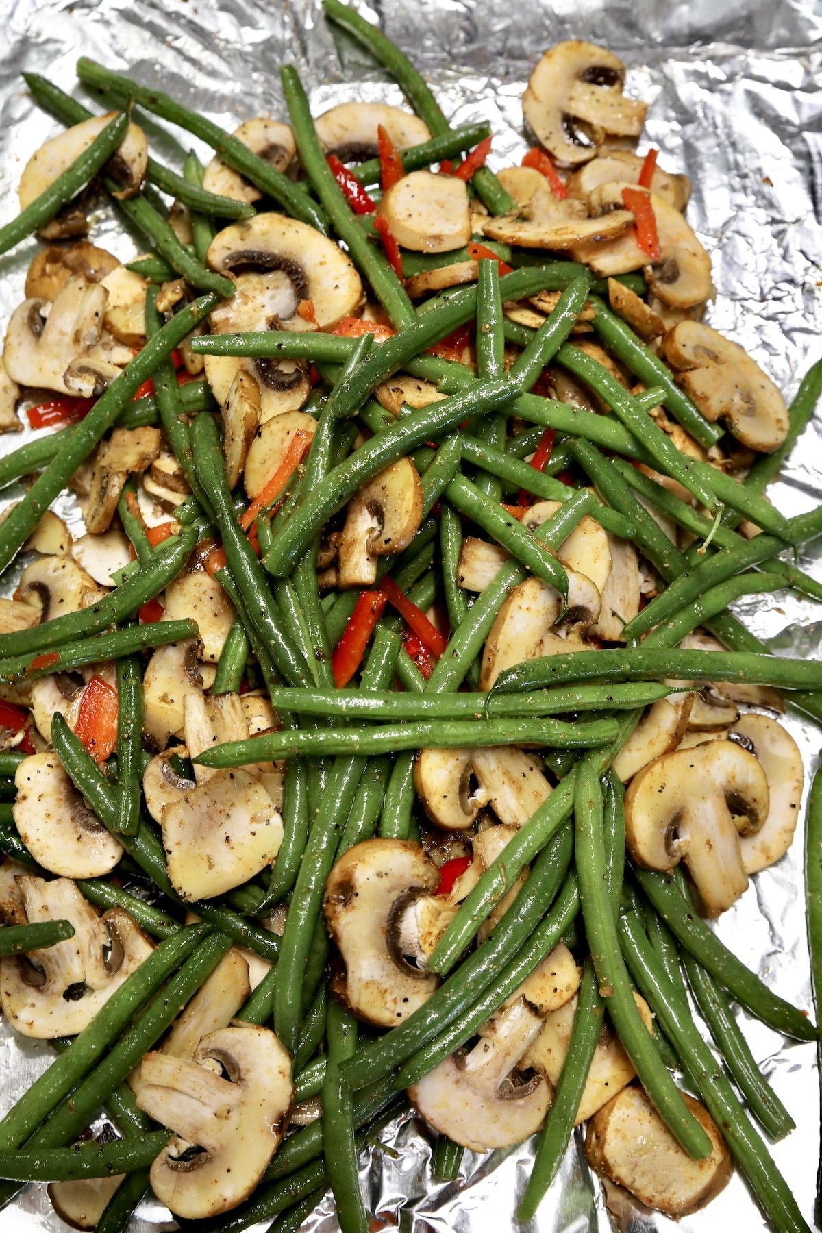 Green beans mushrooms tossed together on foil.