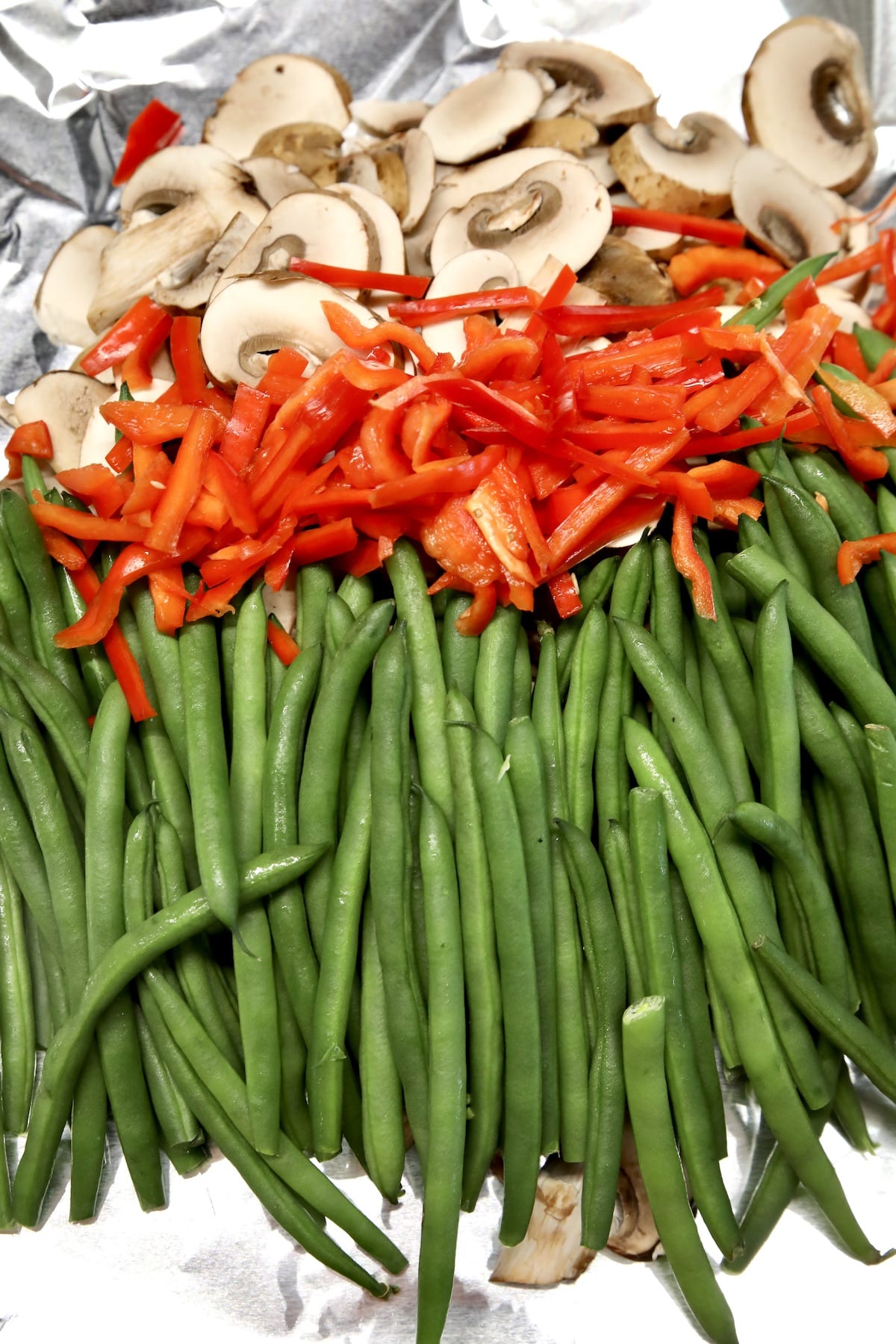 Foil with green beans, red bell peppers, mushrooms.