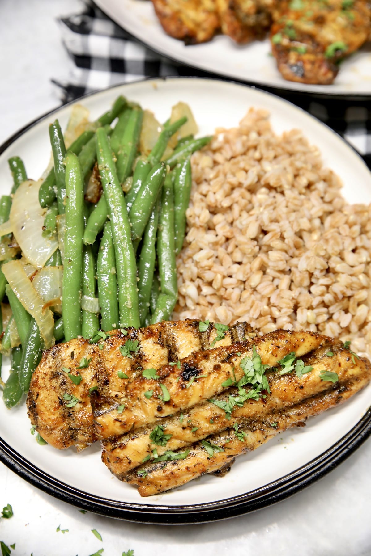 Chicken tenders on a plate with farro and green beans.