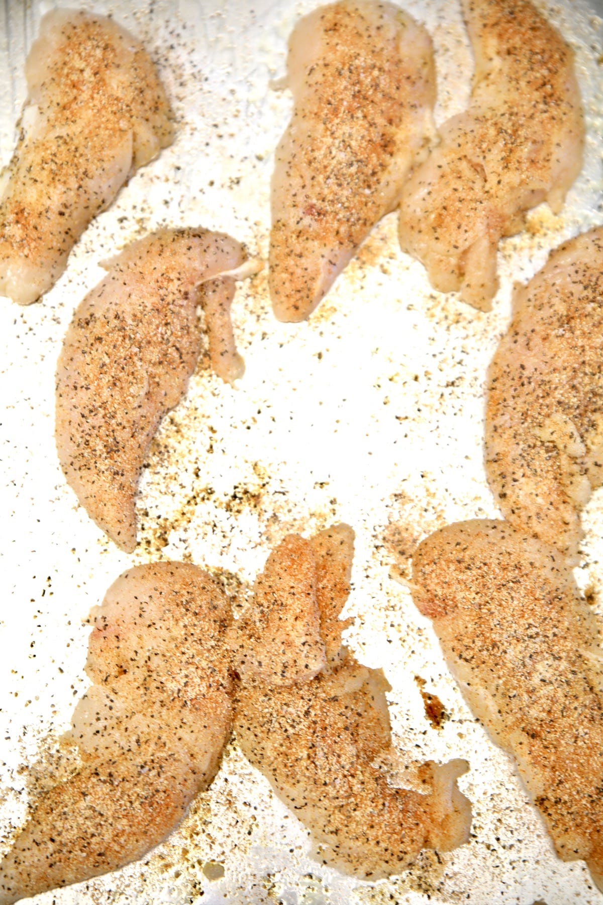 Raw chicken tenders with seasoning.