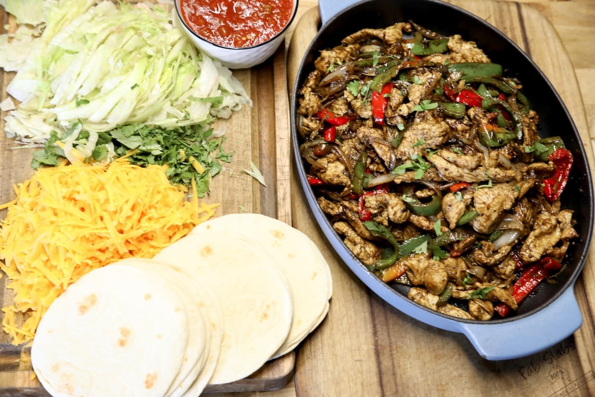 Blackstone fajitas with sliced turkey breast. Platter of fajitas with tortillas, cheese, lettuce, salsa.